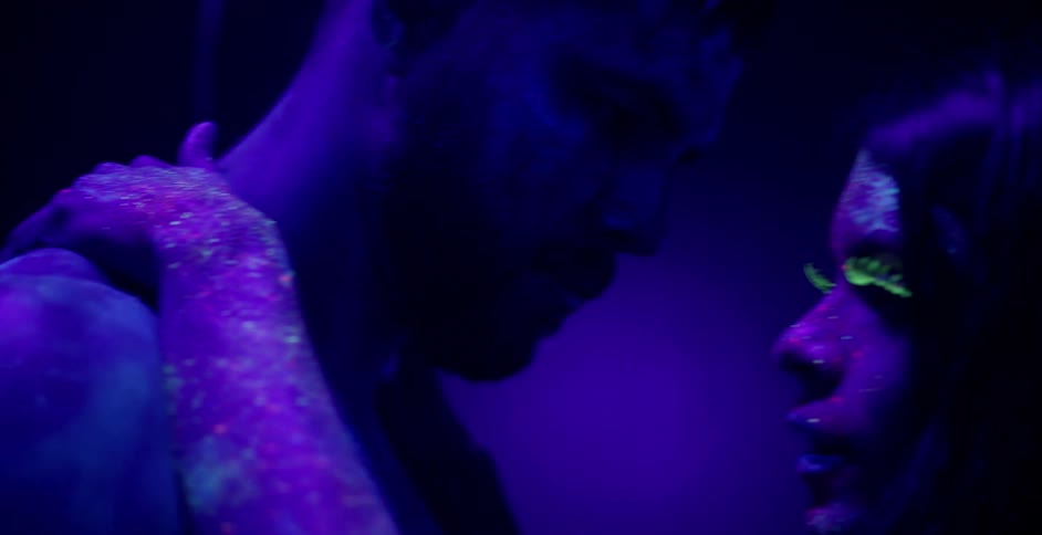 A woman with body paint touches a man