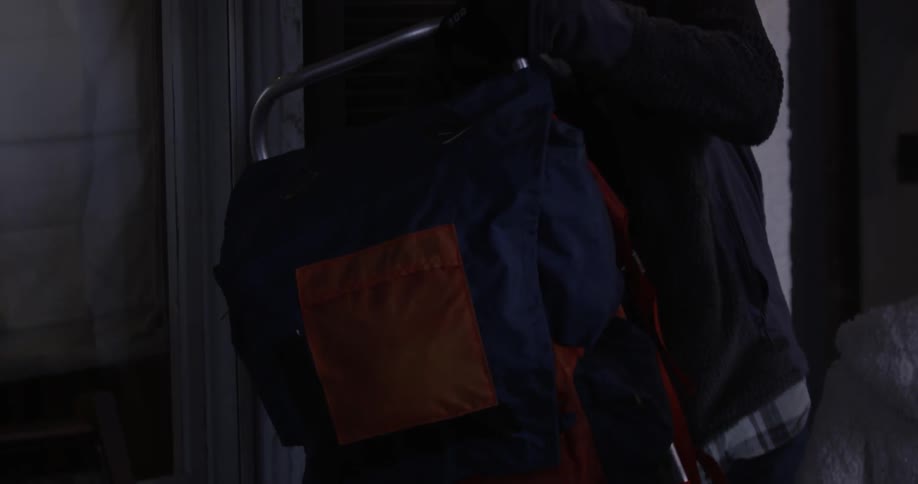 A backpack is sitting on a porch and someone picks it up