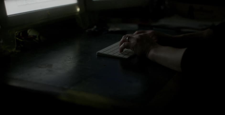 A man types on a keyboard in a dark room