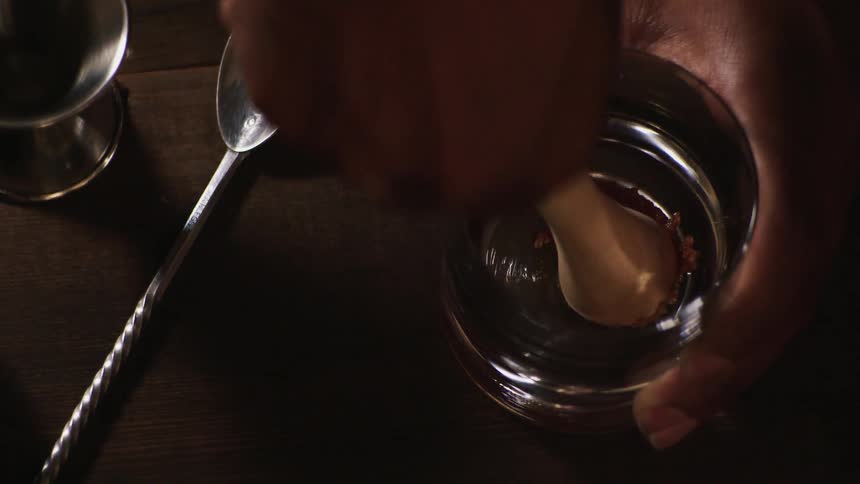 A bartender is smashing a sugar cube