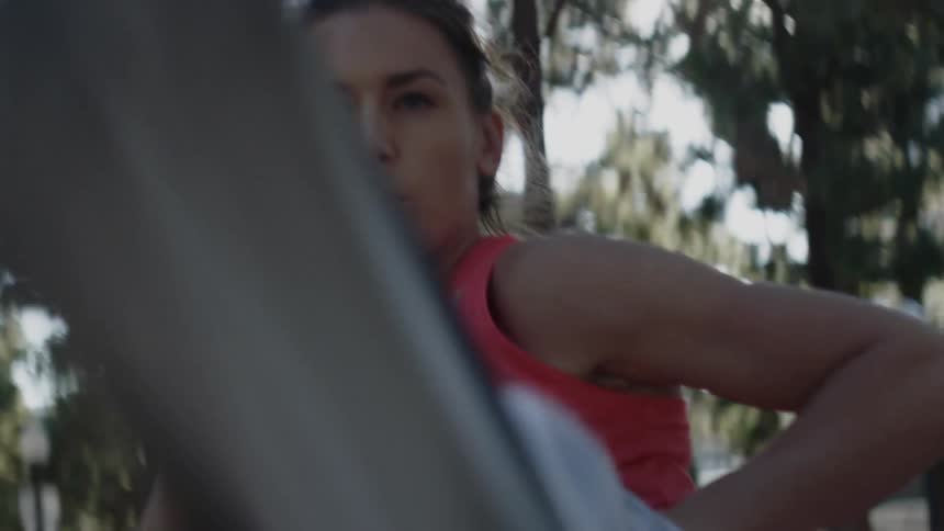 A woman squats and kicks while exercising in a park