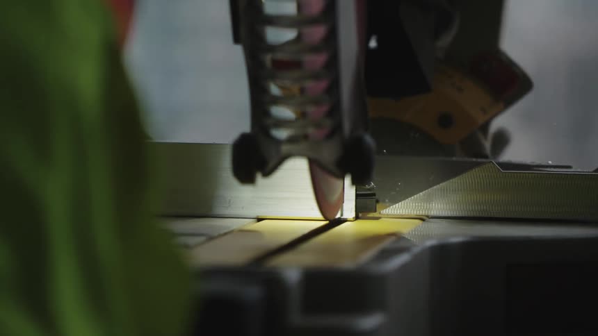 A worker cuts wood with a circular saw