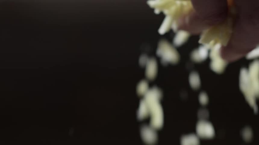 A man sprinkles a handful of grated cheese