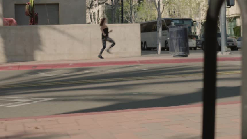 Woman runs down the sidewalk and around the corner