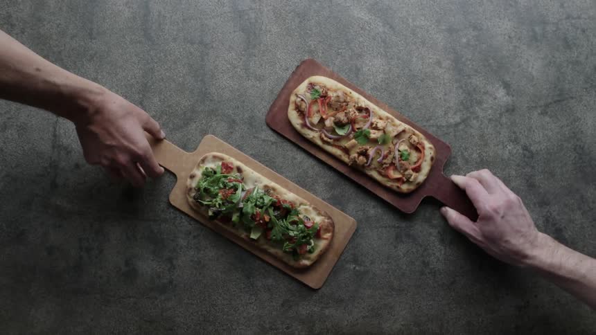 Two people present their pizzas on the table