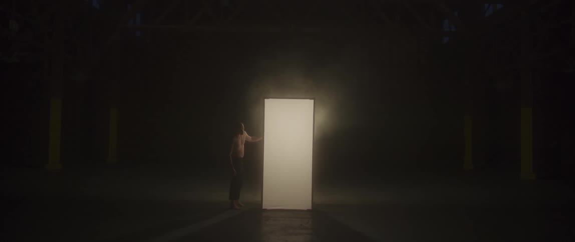 A man stands on the outside of a booth on a stage touching its side