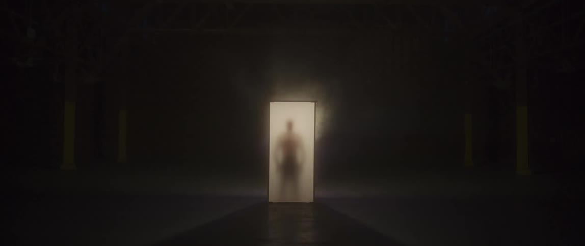 A silhouetted man stands in glowing container