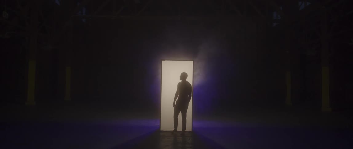 A silhouetted man stands in a glowing column