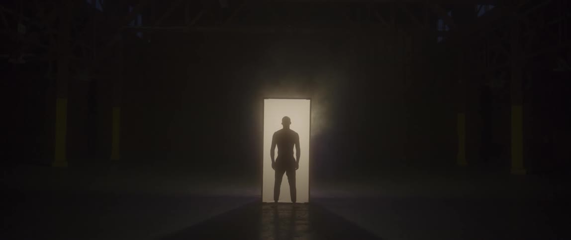 A man stands in a hallway of a dark room