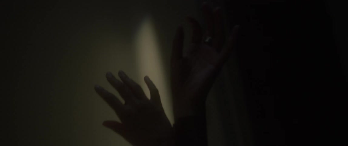 A woman's hands are playing in the light and shadow of a room