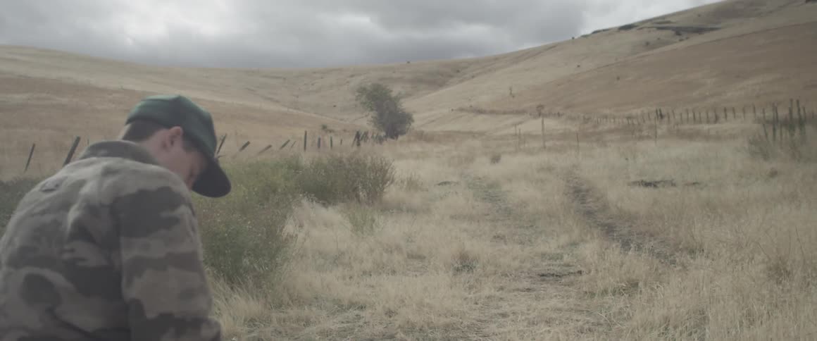 A man is standing in a hilly area on a stormy day