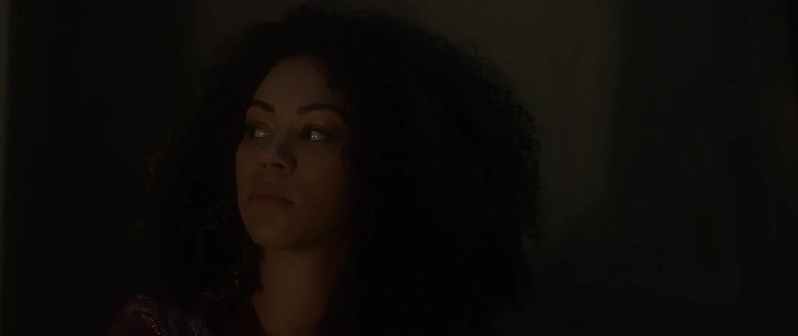 A woman stares out in a dark room