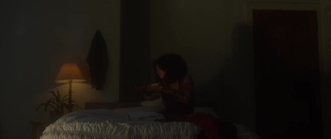 A woman sits on a bed and stretches her arms