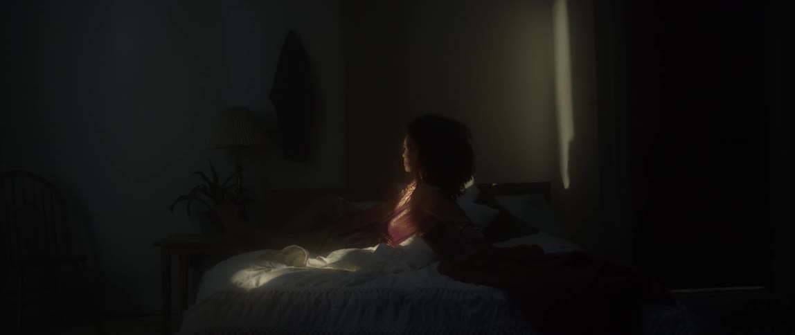 A woman resting on a bed is raising her head toward the sunlight