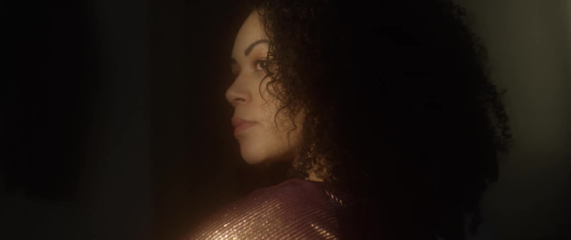 A woman looks to her side in the dark