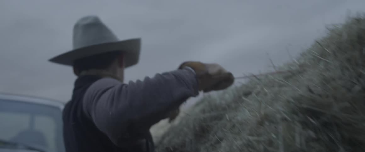 A man carries a hay bale to a truck