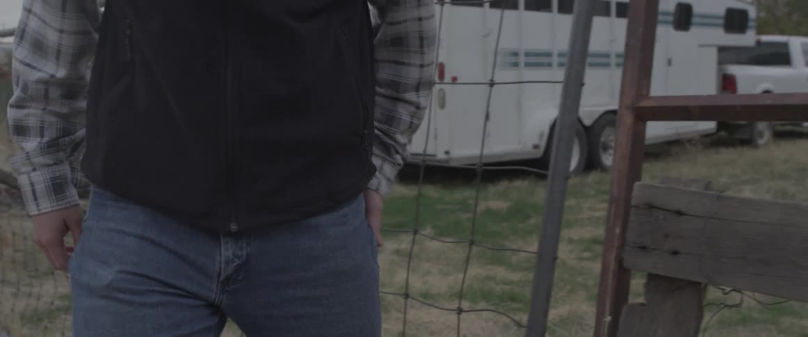 A cowboy closes a metal gate