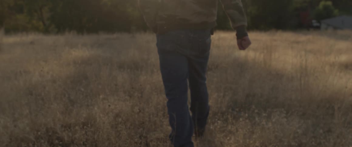 Man walks in a field of tall grass in the country