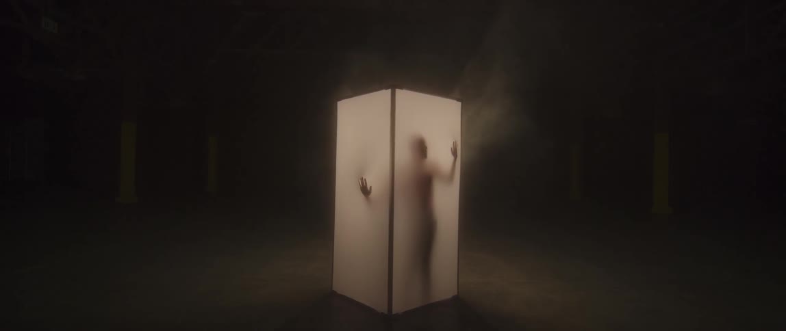 A person stands up in a white lit fabric screen box