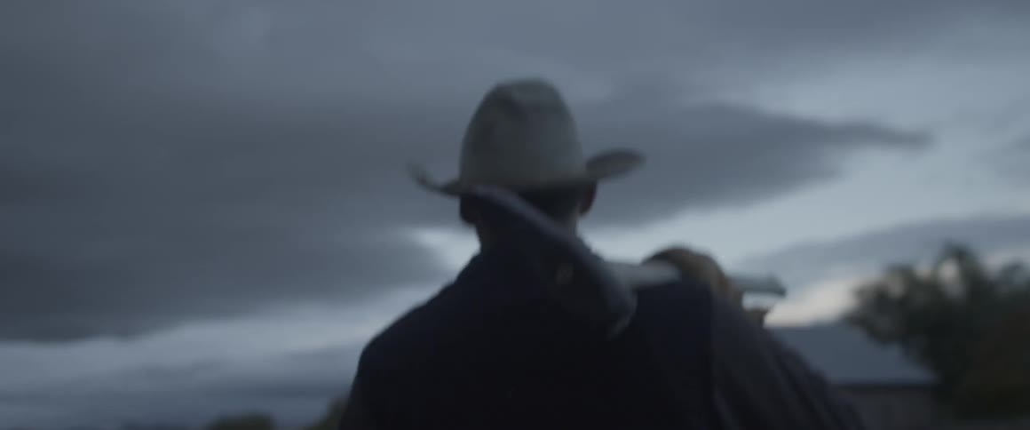 A man walks across the field at dawn