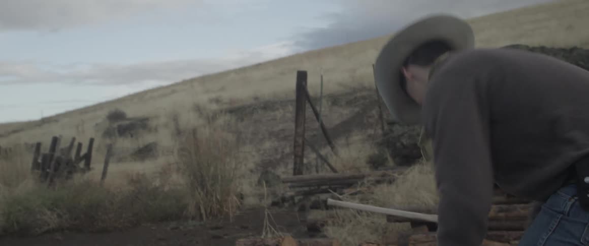 Man picks up logs and throws them in a pile