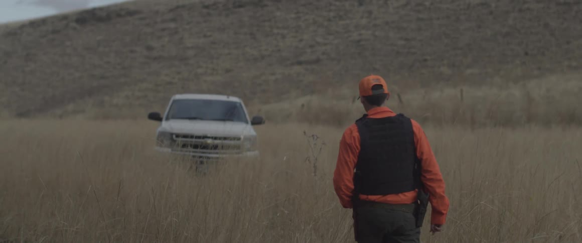 A man approaches a truck parked in a rural field
