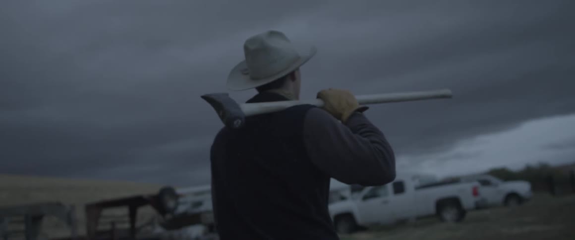 A man carries a hatchet towards a truck
