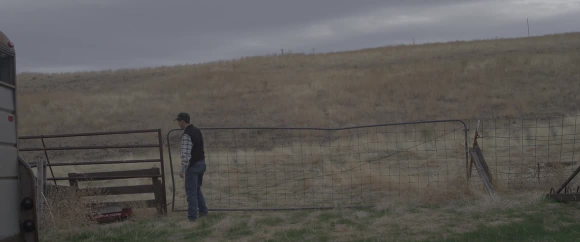 A man opens a farm fence