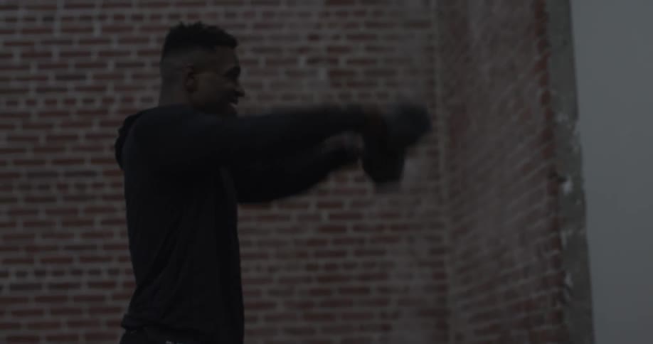 A man is lifting free weights by a building