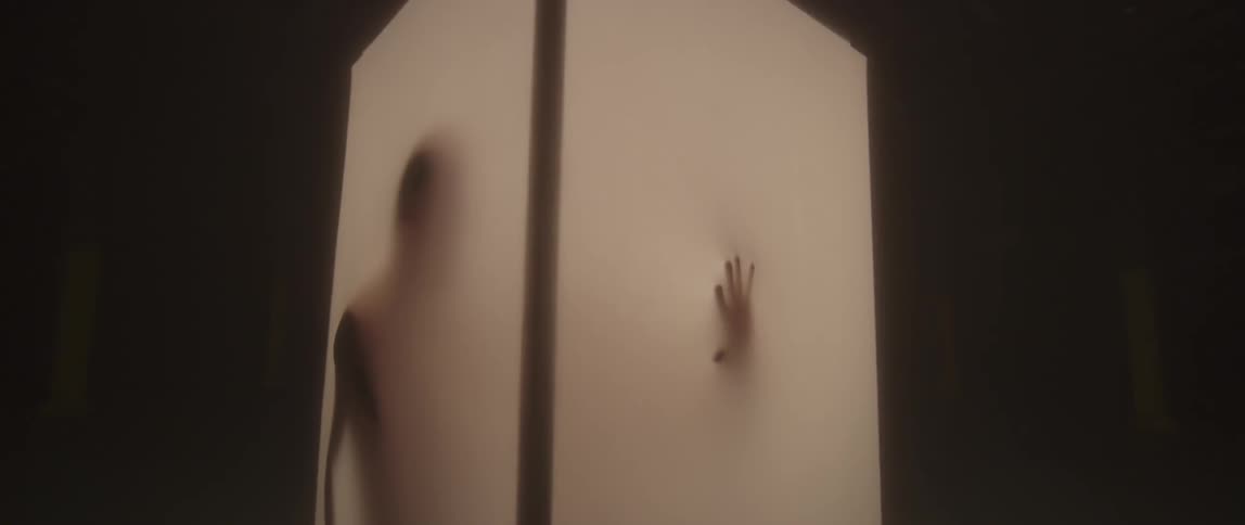 A silhouetted man stands in a glowing column and presses his hand against the wall