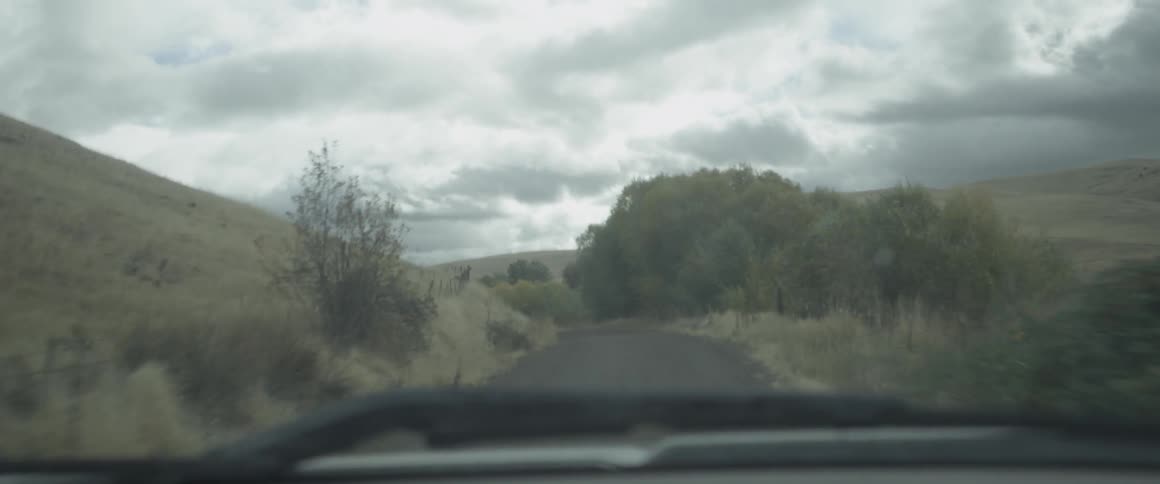 A vehicle drives down a narrow rural road