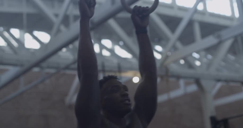 A man is doing pull ups on rings