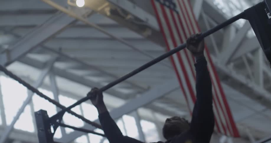 A man is doing pull ups in a gym