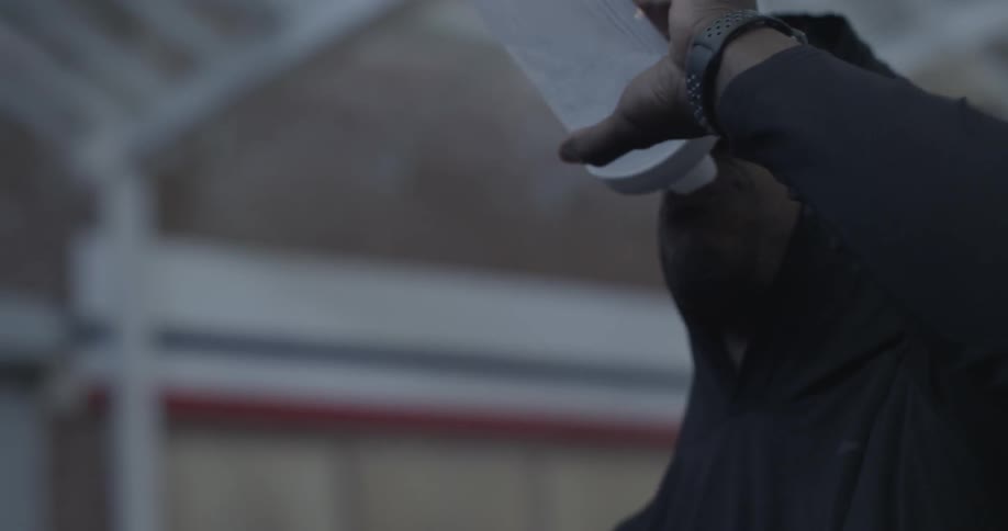 A man wearing a jacket takes a drink of water