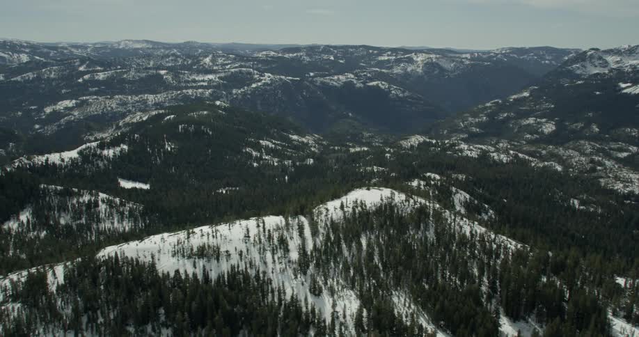 An aerial view of snow covered forest and mountains