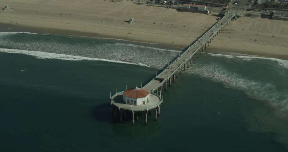The pier goes out into the ocean on the beach off the Coast of California