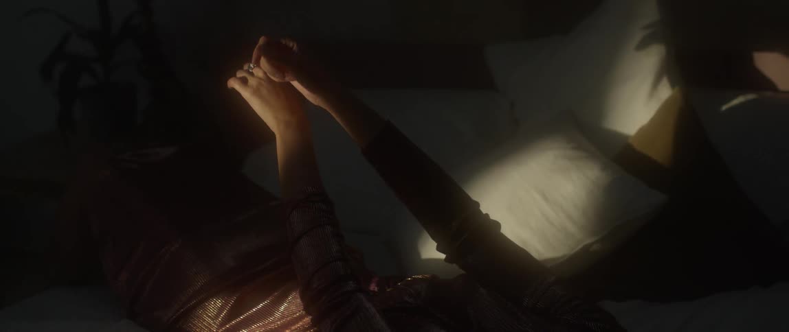 A woman is lying in bed and moving in her hands and fingers