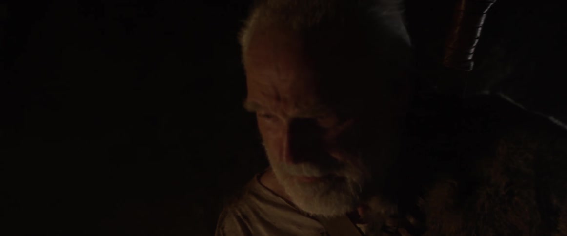 An angry looking man runs in a dark cave and stops