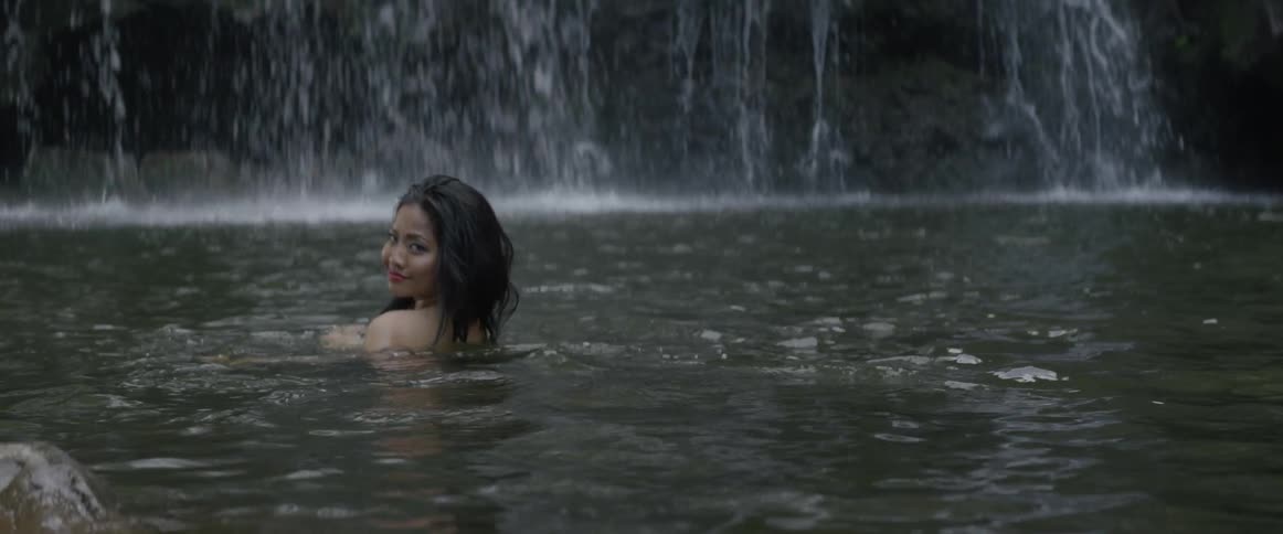 Woman in a pool of water next to a waterfall