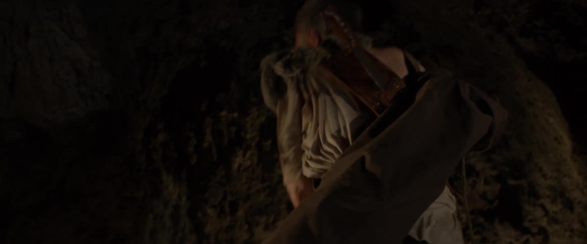 An older man is pulling a rope from a cave wall