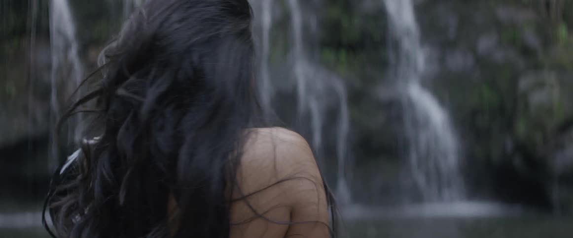 Woman with long dark hair looks over her shoulder