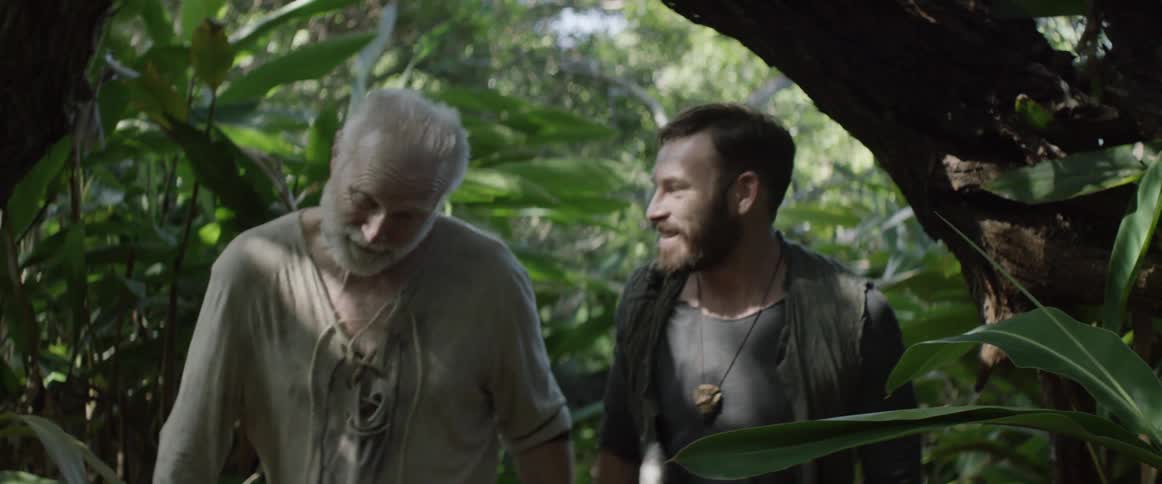 Two men smiling and walking through the forest together
