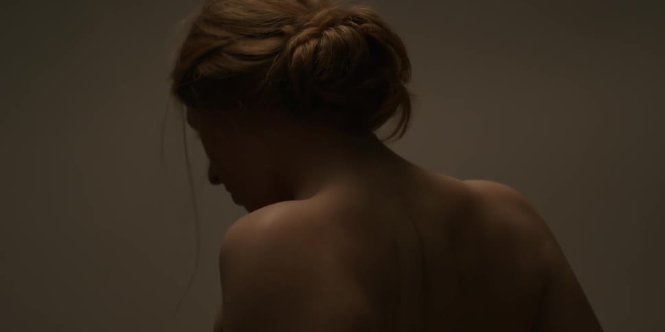 A woman is shrugging her shoulders in a dark room