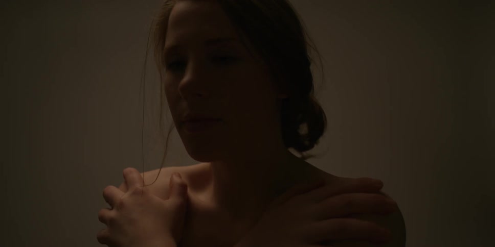 A naked woman is arching her head and caressing her shoulders