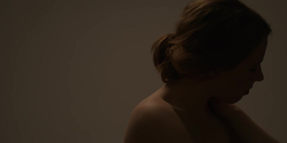 A naked woman rubs her arms on her shoulders and upper back