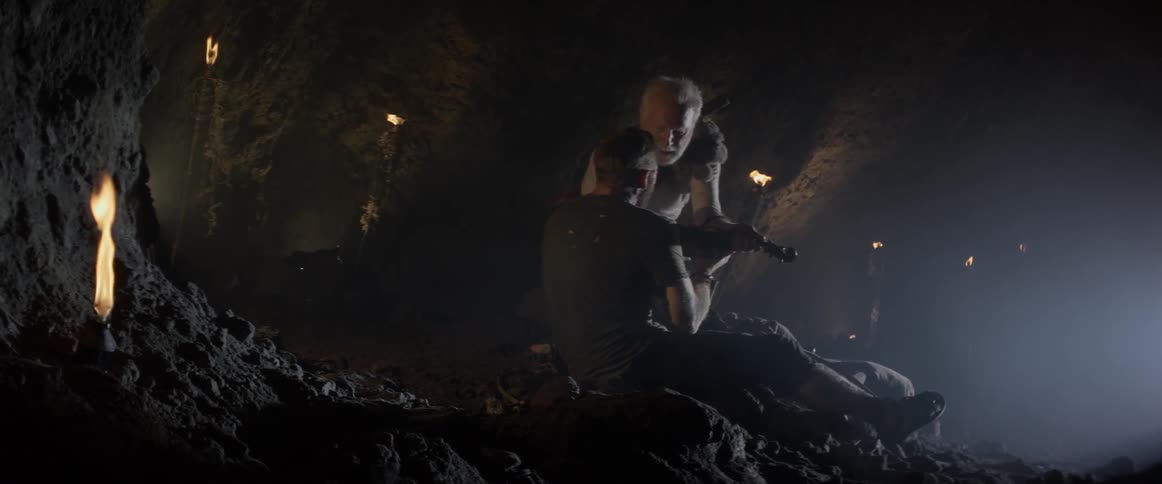 A man is presented with a violin in a dark cave