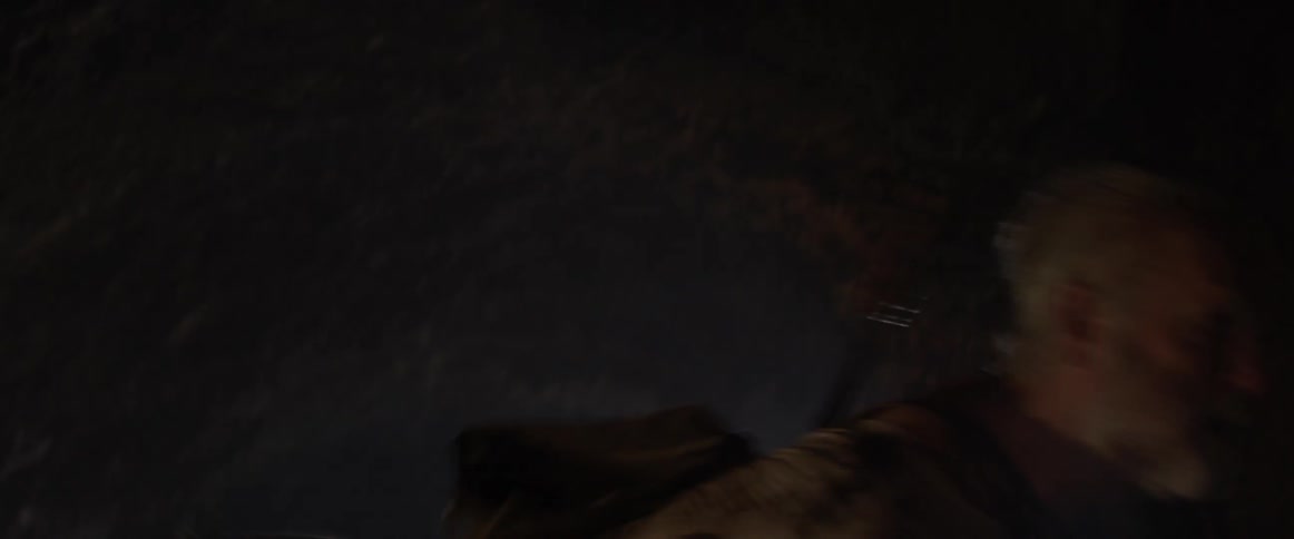 A man screams and swings his arm while walking in a dark cave