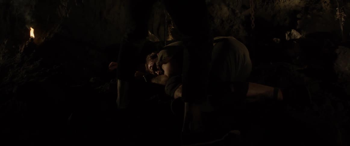 A man stands over an injured person with a sword