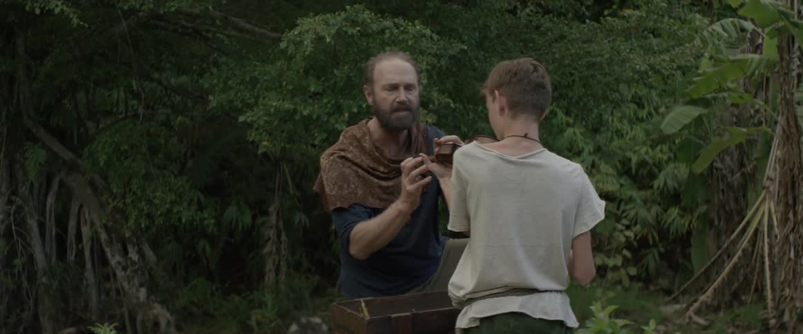 A man is showing a boy how to hold a violin