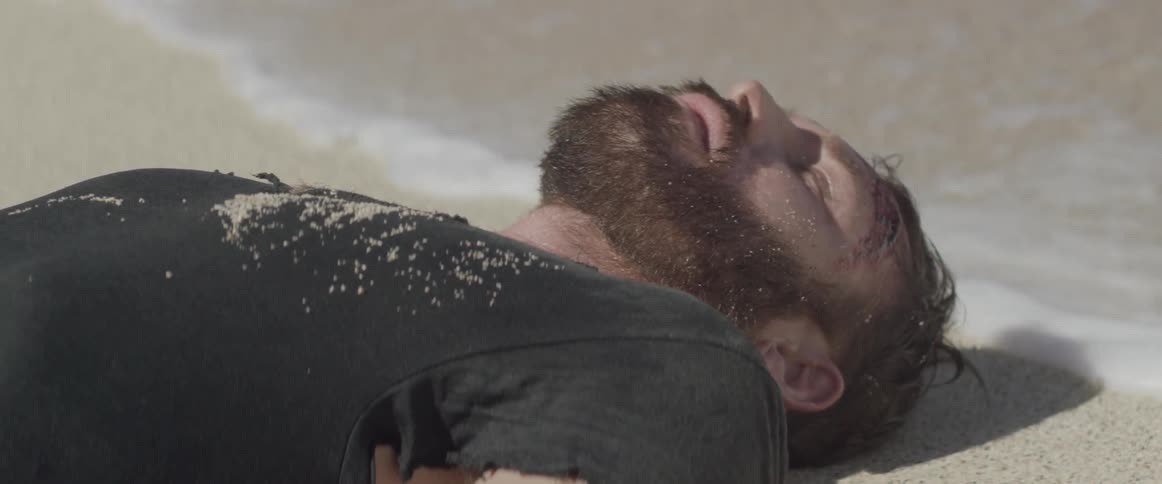 Man lying unconscious on beach as waves wash up